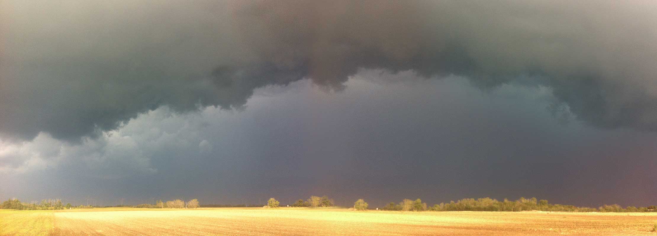 Acker im Sonnenschein mit dunklemRegenwolkenhimmel